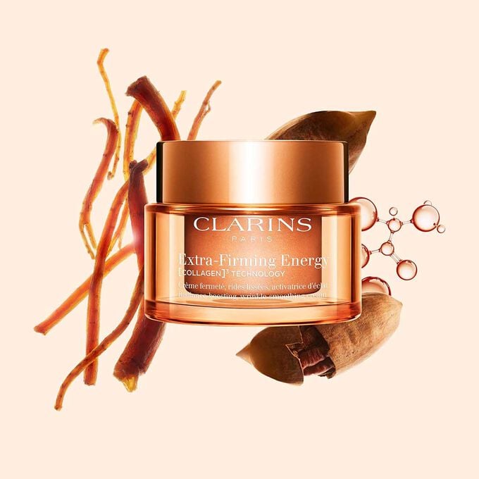 Packshot della crema Extra-Firming Energy di Clarins accanto a Ginseng Rosso, molecola di Collagene e Mitracarpus su sfondo beige
