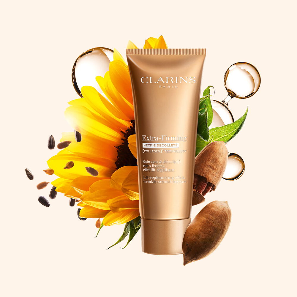 Packshot del prodotto Extra-Firming Crema Collo e D&eacute;collet&eacute; di Clarins, circondata da collagene, noci pecan e girasole per mettere in risalto i suoi ingredienti chiave.
