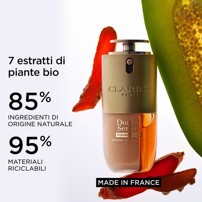Packshot di Double Serum Foundation vicino a curcuma e papaia, per mettere in evidenza gli ingredienti naturali e l&rsquo;etichetta Made in France
