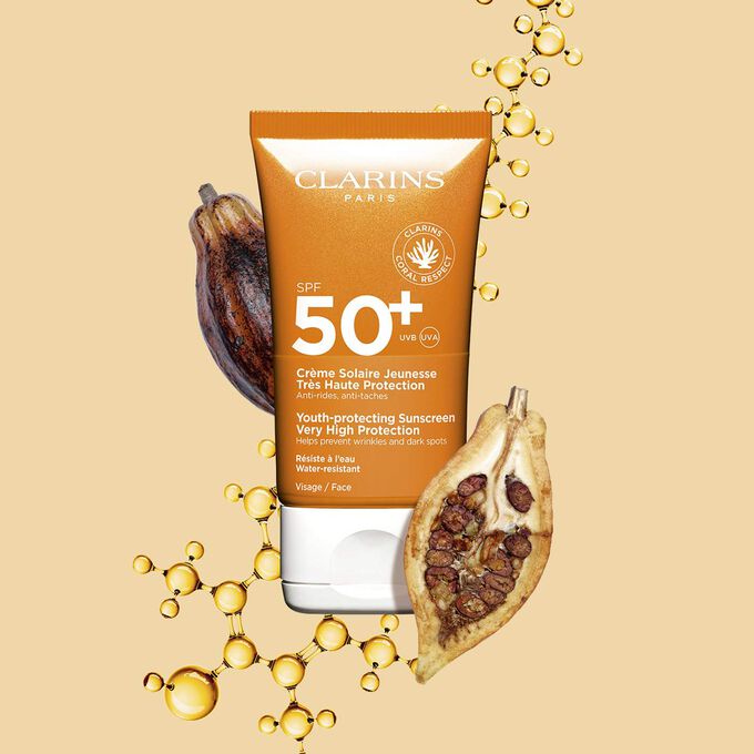Packshot del tubetto arancione scuro di crema solare waterproof spf 50 vicino a fave di cacao su sfondo arancione chiaro