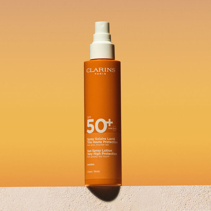 Packshot spray di lozione solare corpo fattore 50 con un messaggio che annuncia l&rsquo;impegno Clarins a tutela dell&rsquo;ambiente
