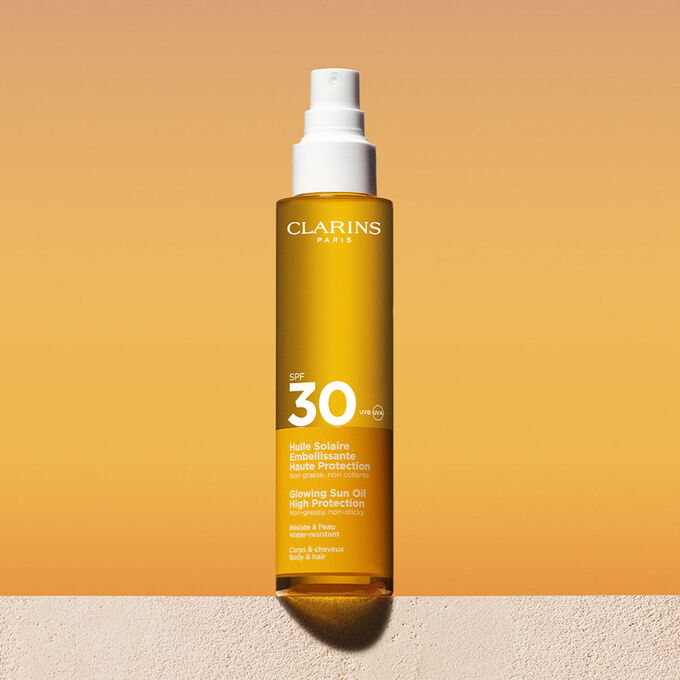 Packshot uno spray di olio solare 30 capelli e corpo con un messaggio che annuncia l&rsquo;impegno Clarins a tutela dell&rsquo;ambiente