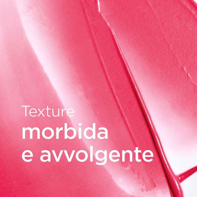 Sfondo rosa cremoso testurizzato con testo che evidenzia la texture morbida e fondente del balsamo labbra della collezione Love per labbra levigate