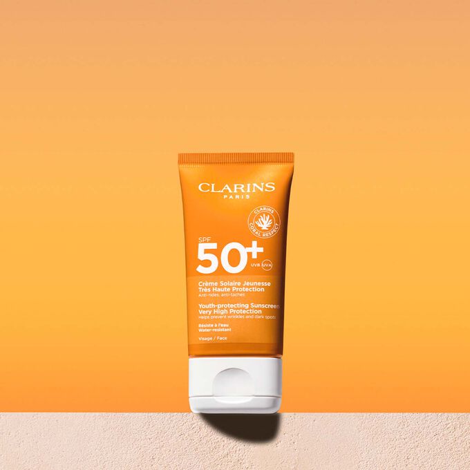 Packshot tubetto di crema solare viso fattore 50 con un messaggio che annuncia l’impegno di Clarins a tutela dell’ambiente