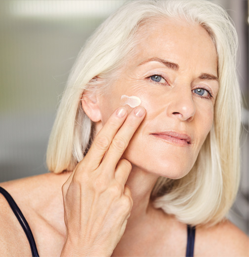 Una donna matura che applica una crema viso